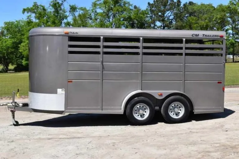 Tan 2017 CM 3HSLBP 3 horse bumper pull trailer with slatted stock sides, full side view on a sandy lot